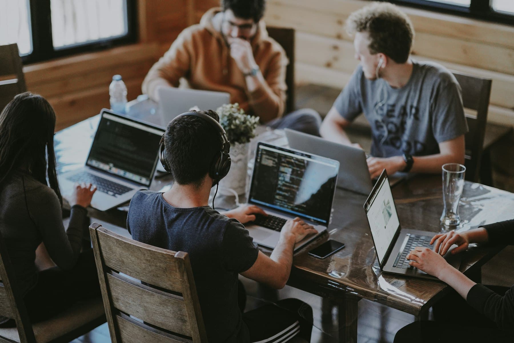 Several colleagues gathered around a laptop in a bright office, talking through work on the screen.