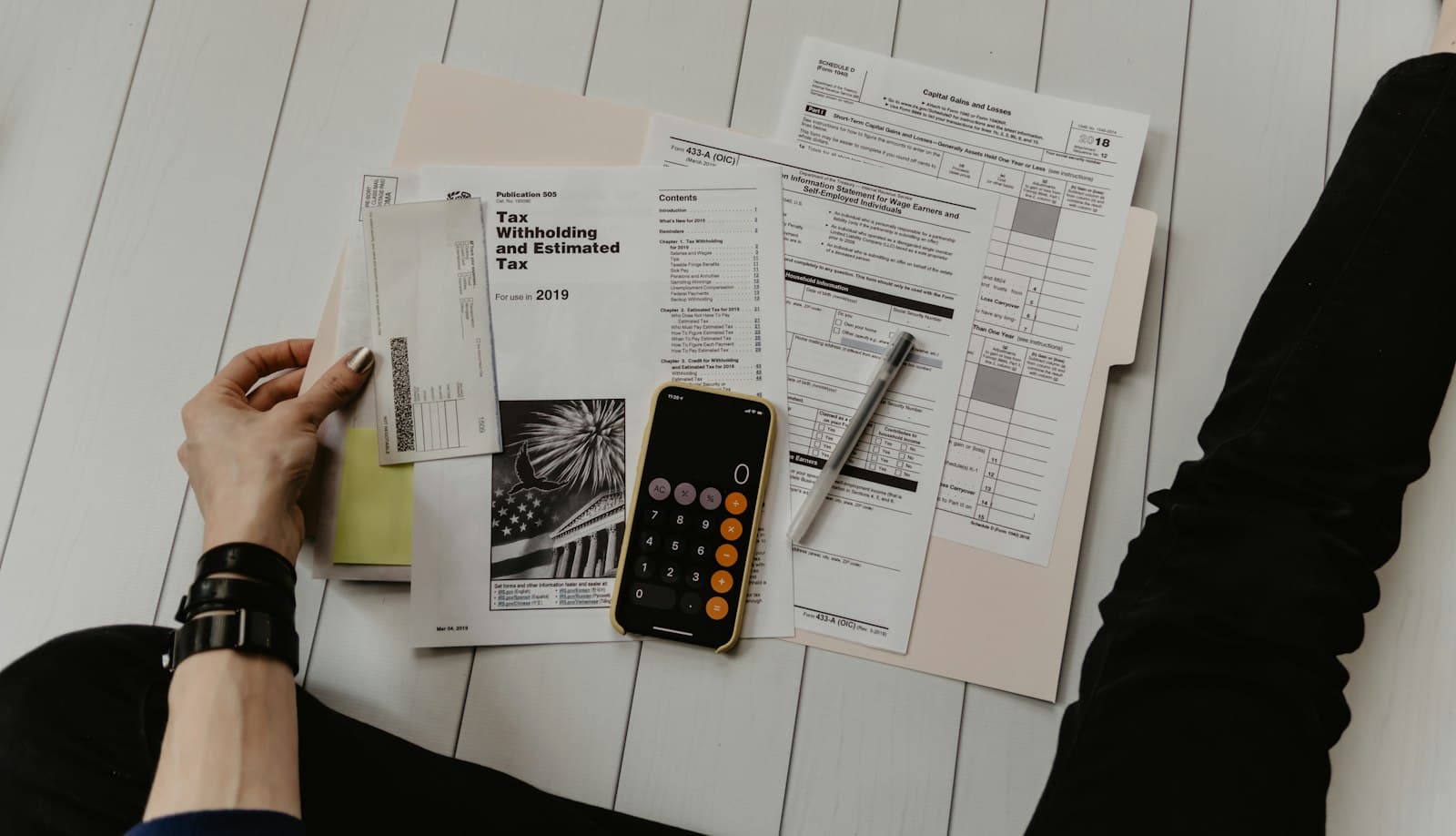 A person reviewing printed financial documents beside a calculator.